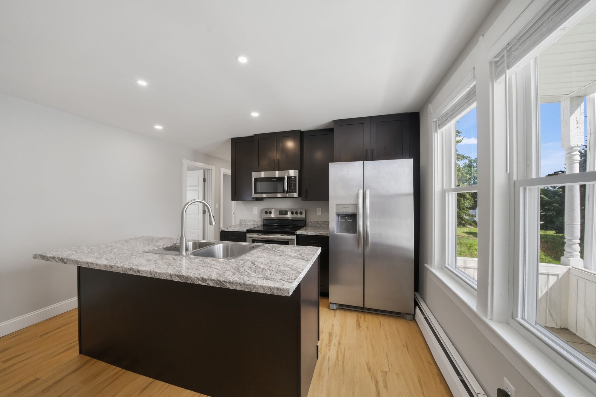 Kitchen with a granite island, dark cabinets and stainless appliances